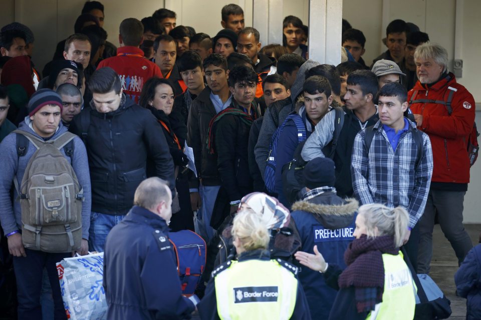 Migrants queue for bus to take them from Calais to reception centres