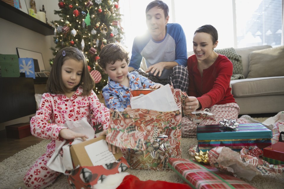 Kids round a Christmas tree opening presents