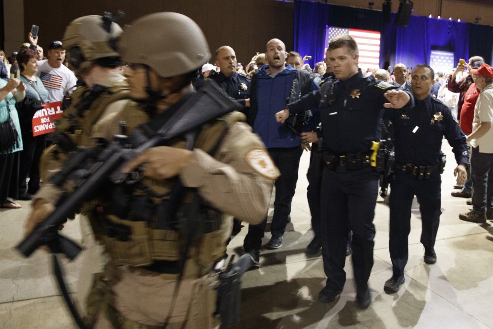 Escort . . . suspect (in blue) is led away by armed cops