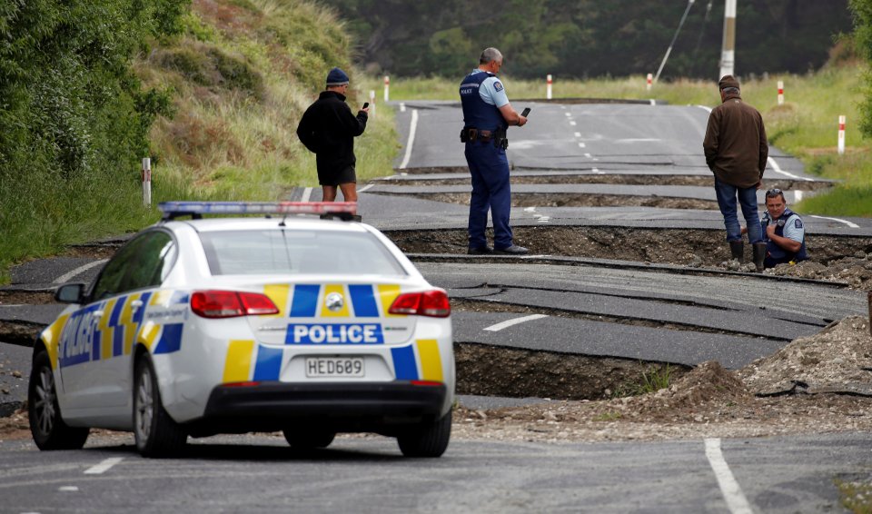Policemen and locals look at damage following an earthquake, along State Highway One near the town of Ward