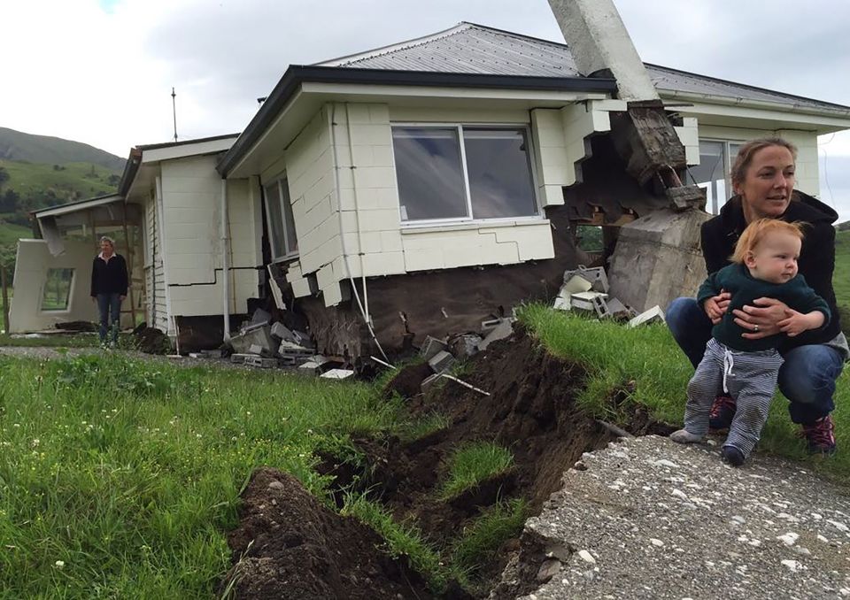 A woman and child in front of a damaged house at Bluff Station near Kaikoura 