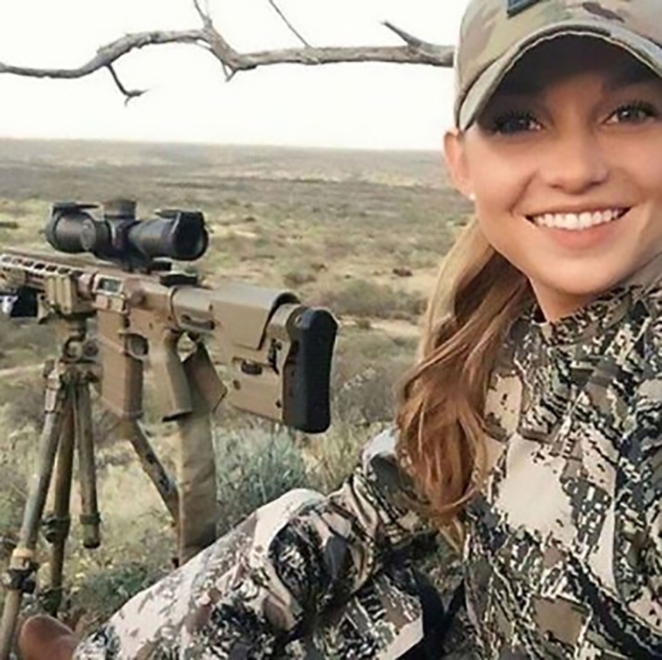 this stunning blonde is pictured looking up from her tripod-mounted machinegun to give the photographer a winning smile.