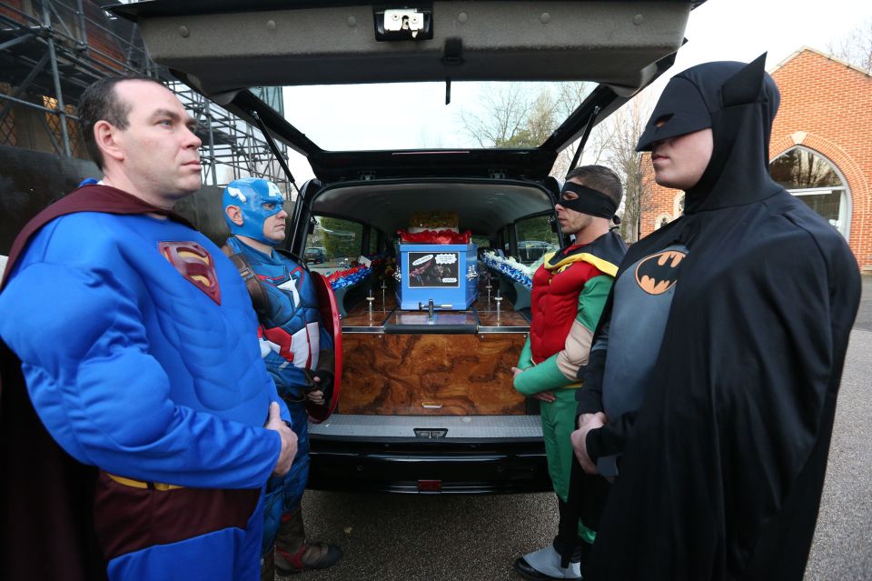 Pallbearers dressed as superheroes prepare to carry the coffin 