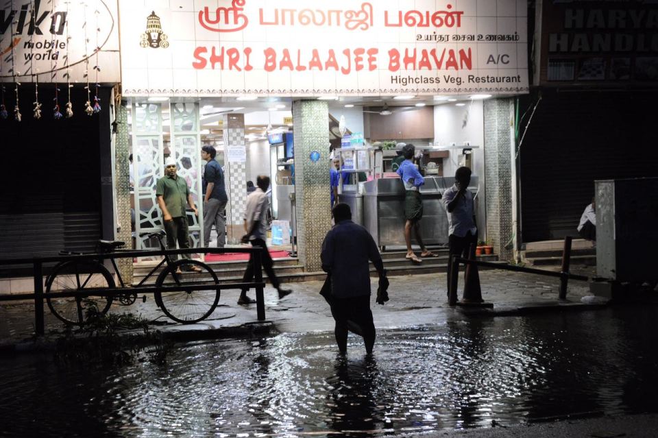 Men walk along a flooded street in Chennai as Cyclone Vardah damaged buildings