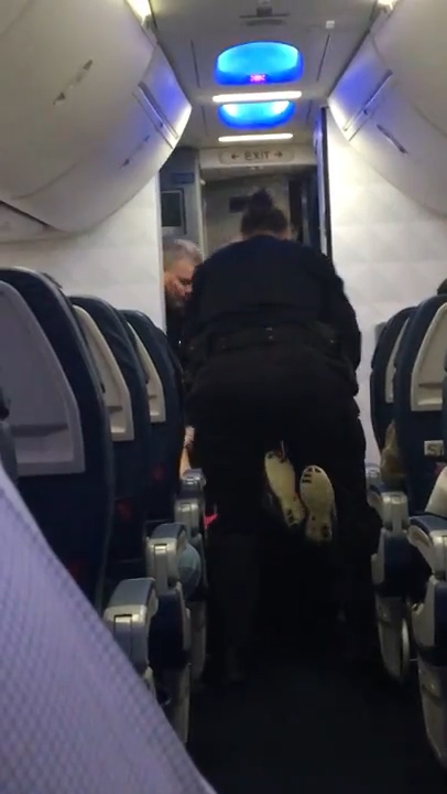 She was then carried off the plane by two officers 