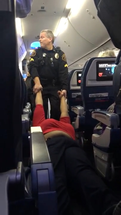 Footage has emerged which shows a woman being dragged off a plane by police