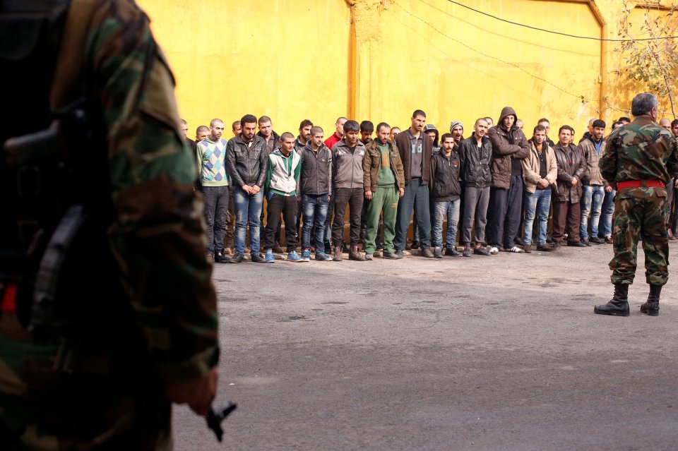 Members of government military police stand guard as men, who were evacuated from the eastern districts of Aleppo, are being prepared to begin their military service at a police centre in Aleppo