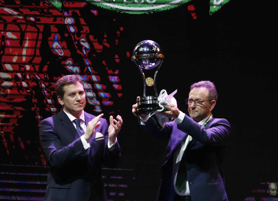The President of Conmebol, Alejandro Dominguez (left), delivers the South American Cup to Plinio David De Nes Filho (right), the President of Brazilian team Chapecoense