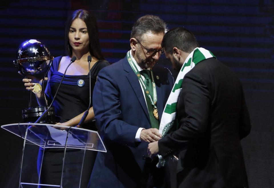 Chapecoense president Plinio David De Nes Filho (centre), presents a Chapecoense scarf of to the representative of Atletico Nacional, Daniel Jimenez