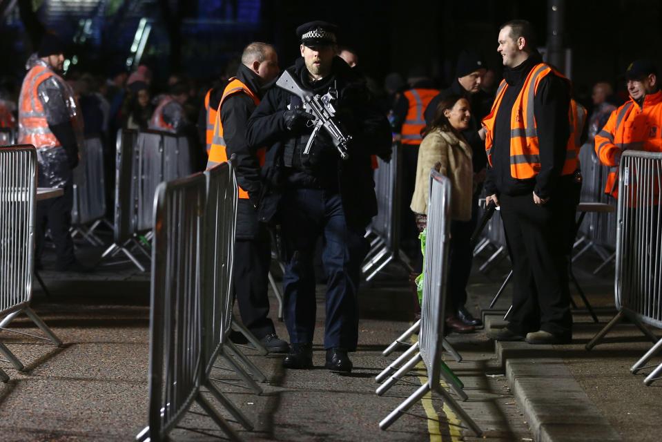 An armed officer patrols the security bag-search area where spectators queue to enter the area to watch the New Year's Eve fireworks in London last year