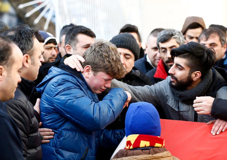 A young man comforts another next to the coffin during the funeral of Ayhan Arik