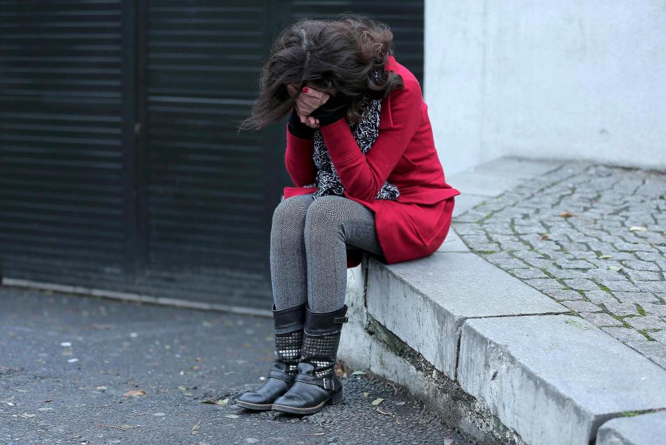 A former employee of the Reina nightclub sobs into her hands in the street
