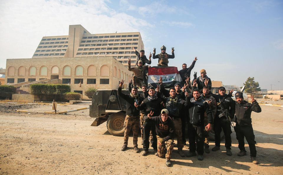 Members of the Iraqi forces pose for a picture outside the Oberoi hotel