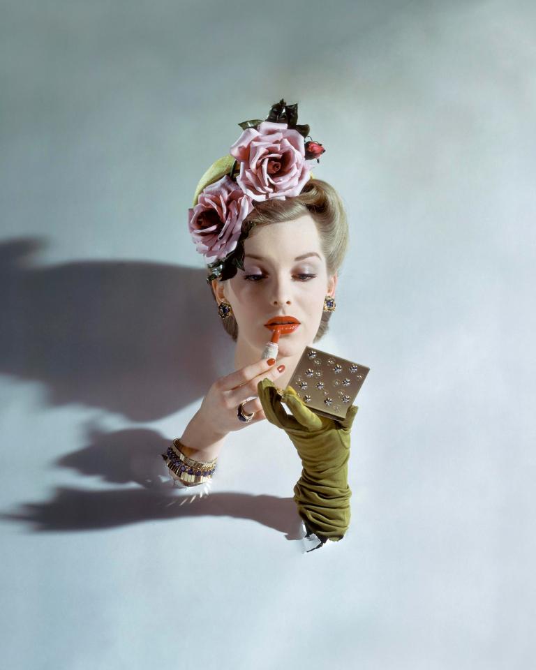  A model with her head and forearms sticking through a white board is seen applying red lipstick (John Rawlings, American Vogue, March 1943 © 1943 Condé Nast)