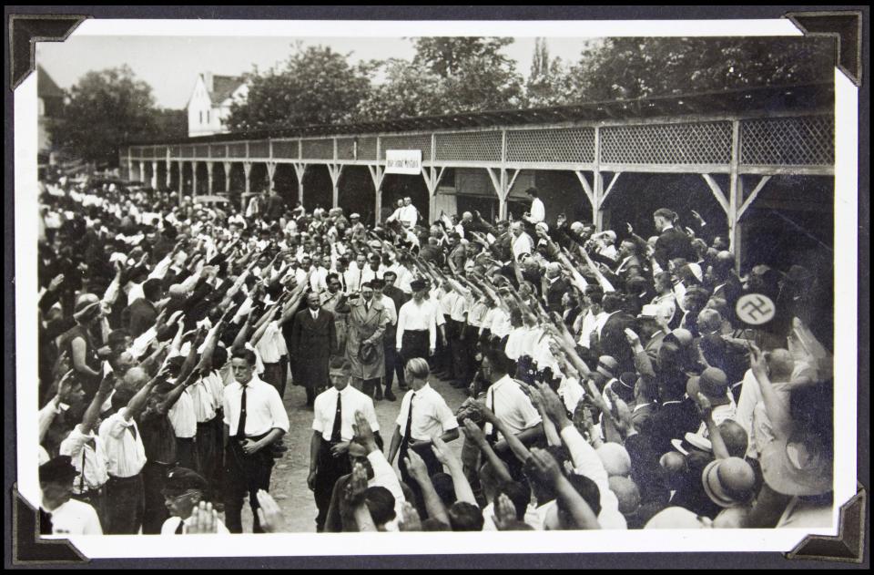 Hitler and his deputy Rudolf Hess receive salutes from members of the Hitler Youth and civilians at a railroad station 
