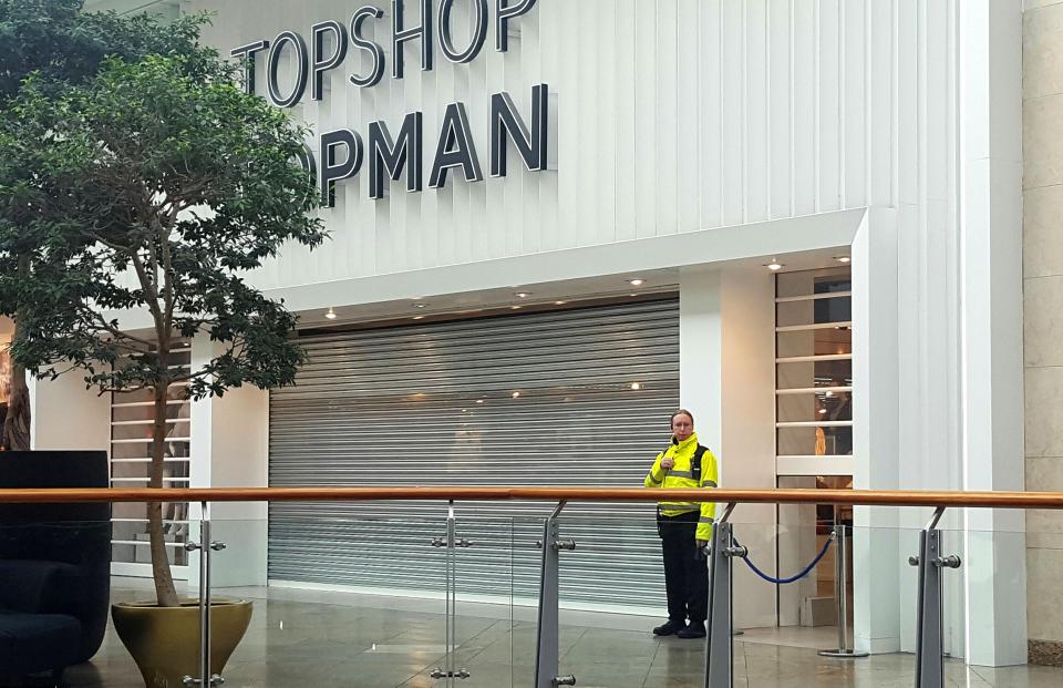 A police officer stands outside the Topshop store in the Oracle shopping centre, Reading, Berkshire, which has remained closed since the incident