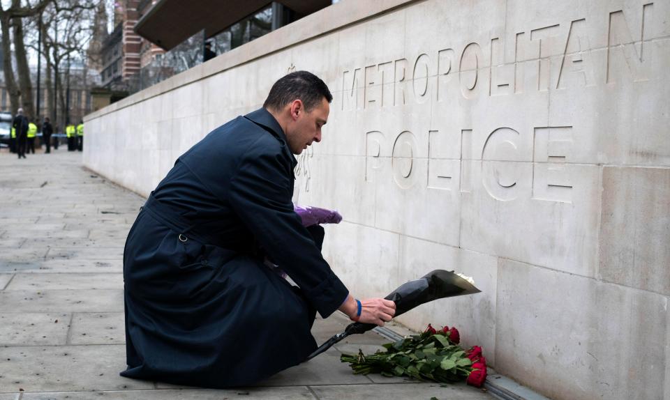 A man lays flowers outside Scotland Yard a day after a police officer was stabbed outside Parliament in a terror attack