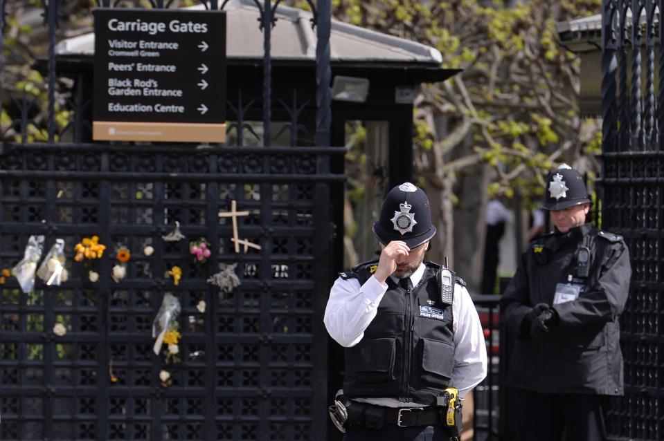  An officer respectfully touches his hat as he stands outside the gate where PC Palmer was stabbed and died
