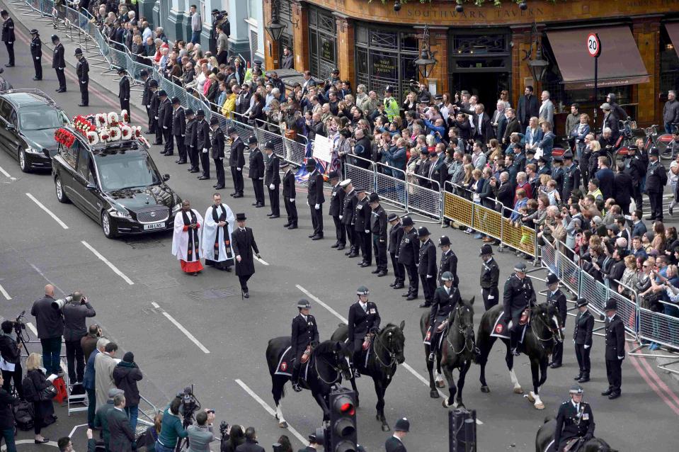  Police officers bow their heads as the hearse carrying PC Palmer drives by past rows of mourners