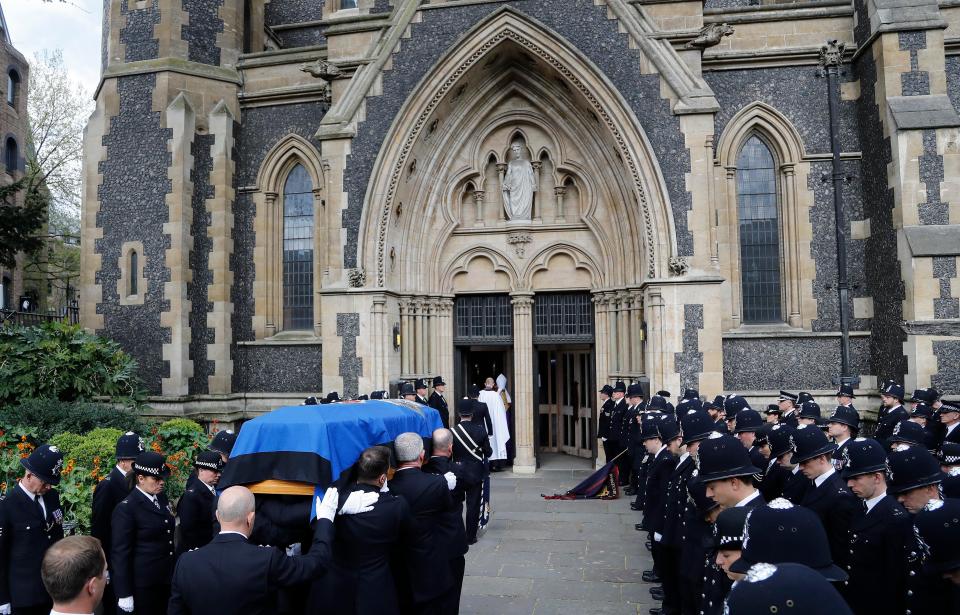  Officers bow their heads as his coffin is carried into the cathedral ahead of the funeral service