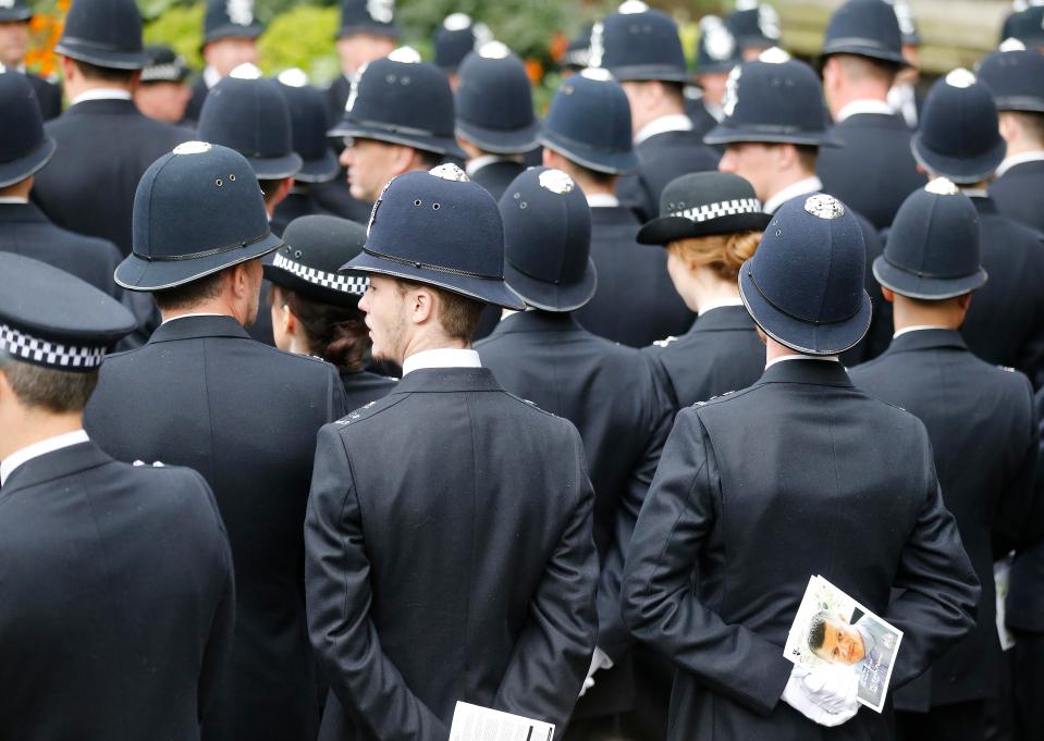  Police officers at the funeral hold the order of service which includes a picture of PC Palmer on the front