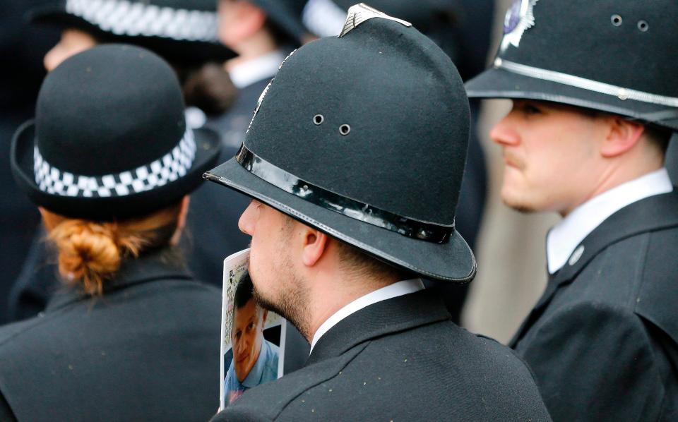  A police officer holds the order of service to his face as he appears deep in thought