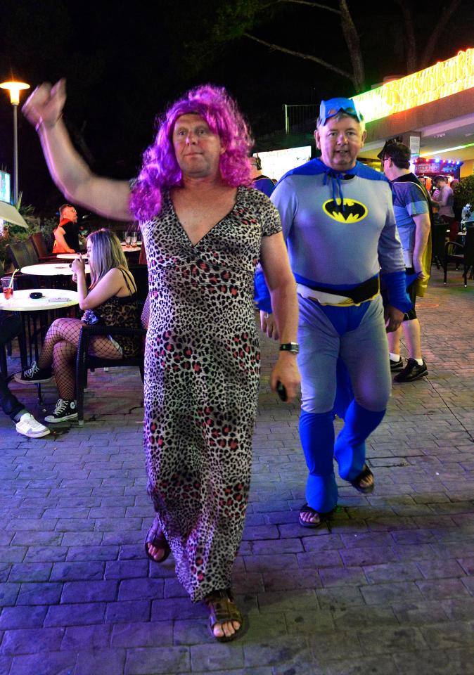  A man in a leopard print dress joins a pal in a batman costume as they head out for a night on the town