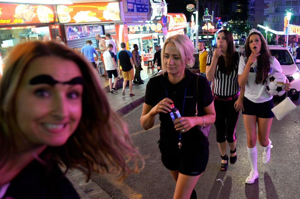  Women dressed in football outfits navigate the busy streets of the party town