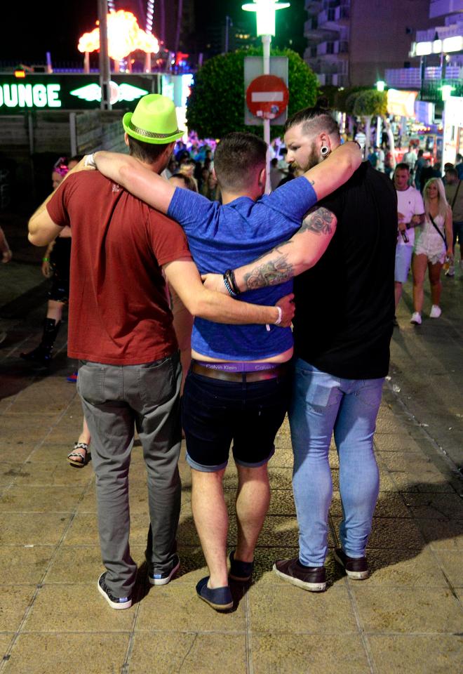  One man appears to have had one too many drinks as his friends help him stumble along the street