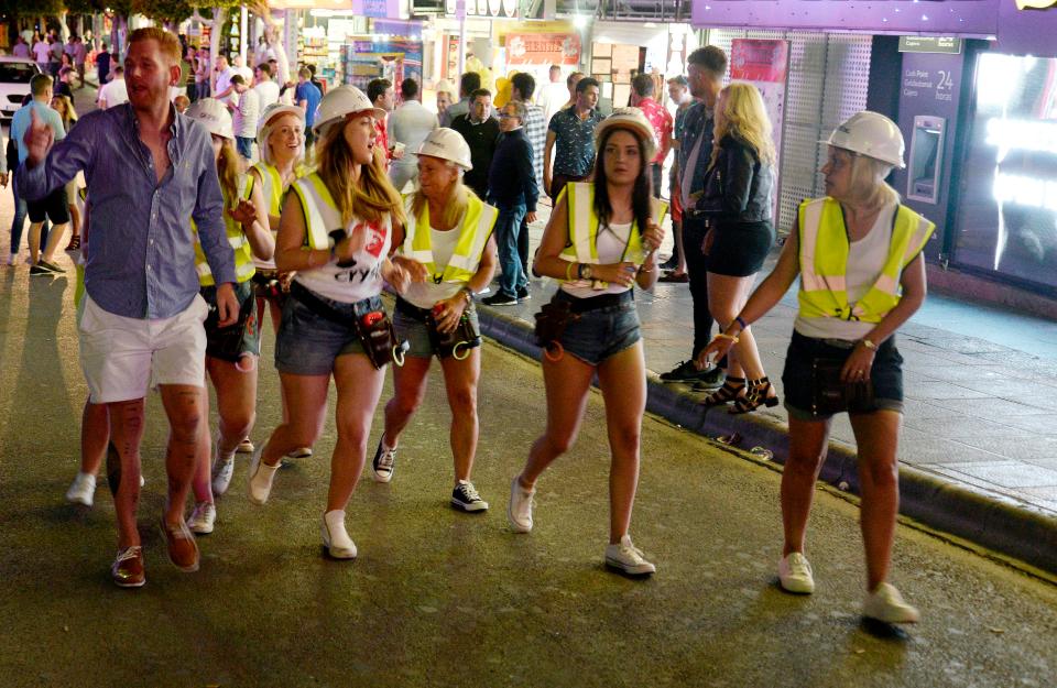  A group of women dressed as construction workers - complete with hard hats and high-vis vests - wander the main strip of Magaluf