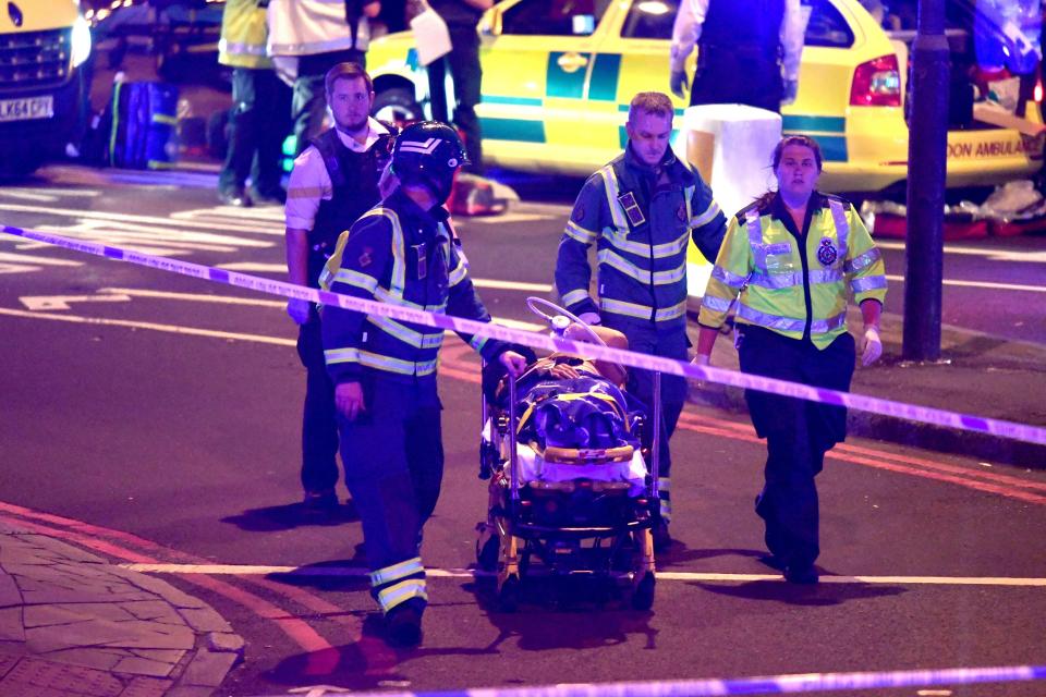 A wounded person can be seen being taken away on a stretcher