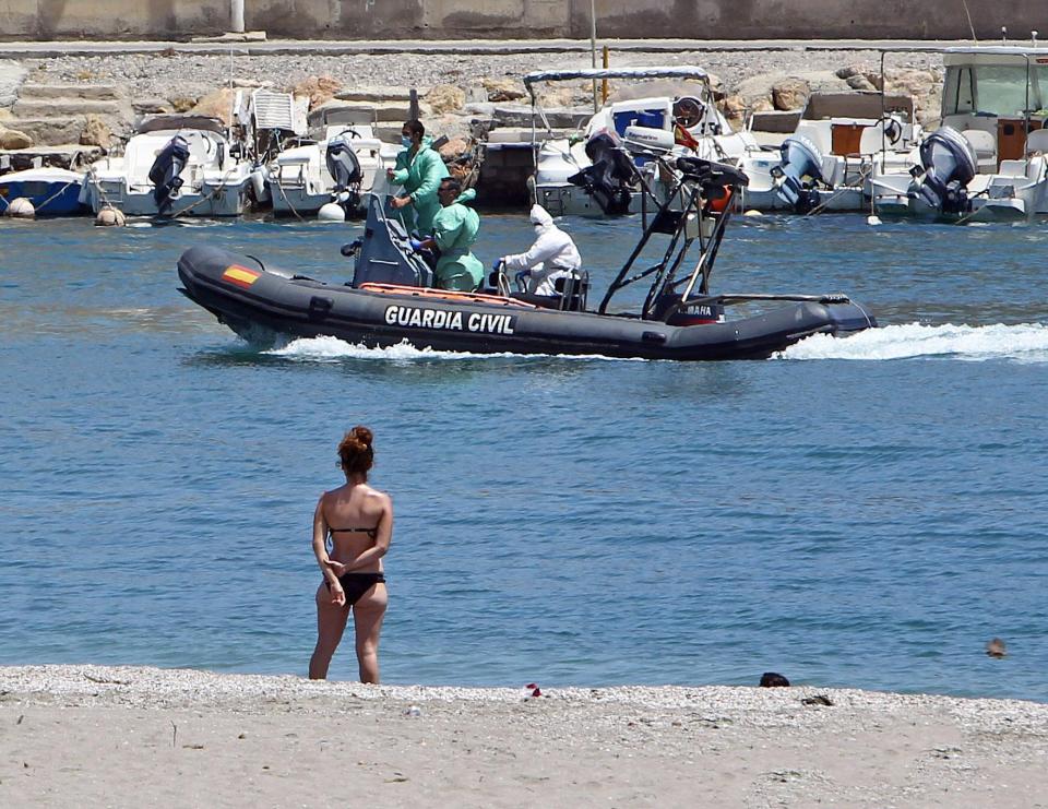 A tourist in Almeria, Spain, watches as police recover a migrant's body