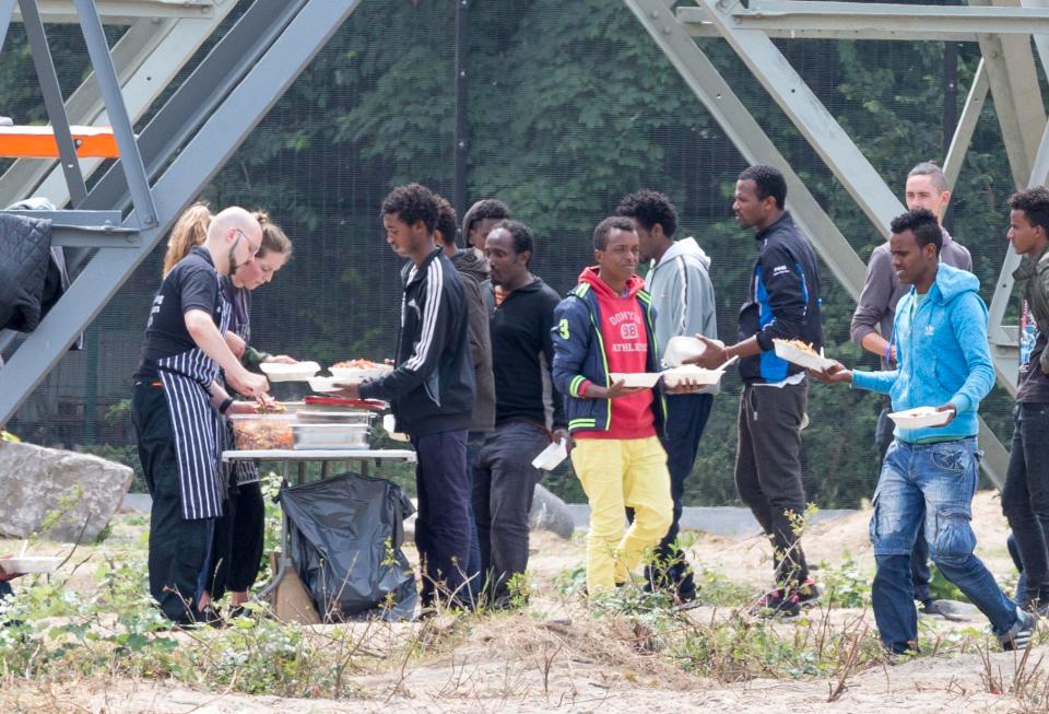  Migrants at the front of the queue are served food by charity staff