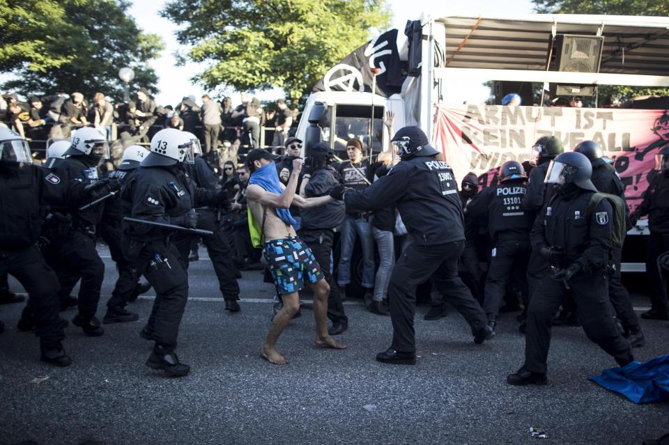  One protester - who has his face covered - is surrounded by police officers