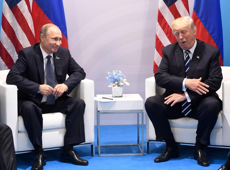  Trump appears to clutch his arm in jest after another round of handshakes with the Kremlin boss