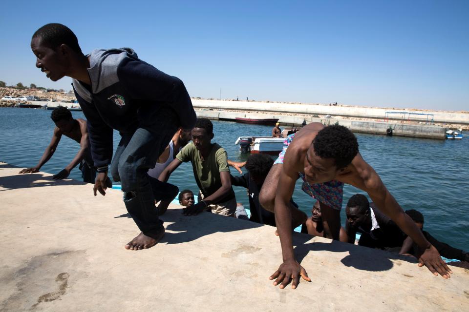  Migrants climb out of a boat after being rescued by the Libyan coastguard