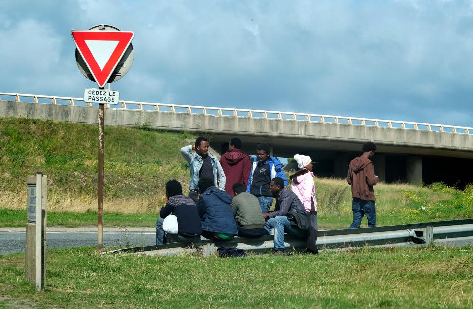  Migrants wait by the Calais highway