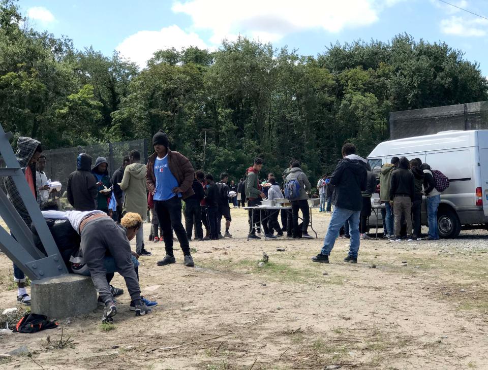 Groups of young men wait for food handouts from a nearby van