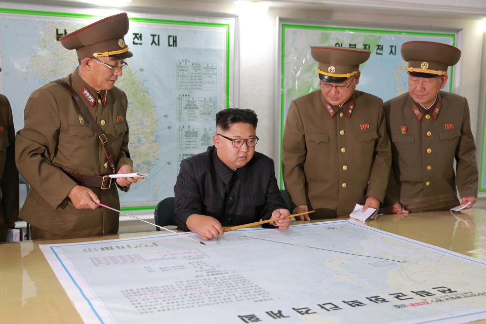 Dictator Kim Jong-un is pictured inspecting plans for a missile attack on US territory Guam