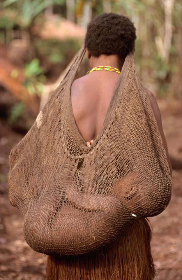 A Korowai woman carrying her child in a net as these amazing pictures taken 17 years ago emerge for the first time
