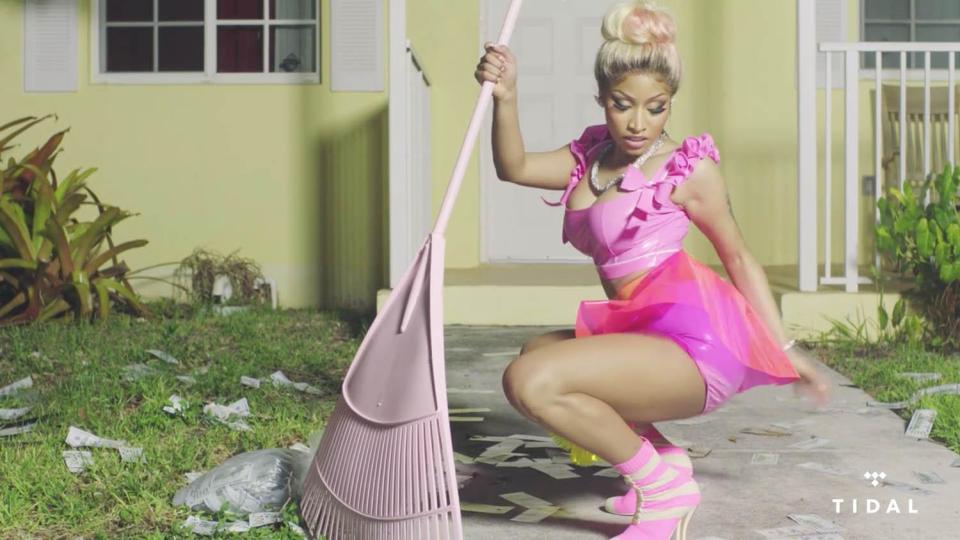  Adding new meaning to the term domestic goddess, Nicki sweeps up outside the front of a house in teetering heels and a skintight outfit