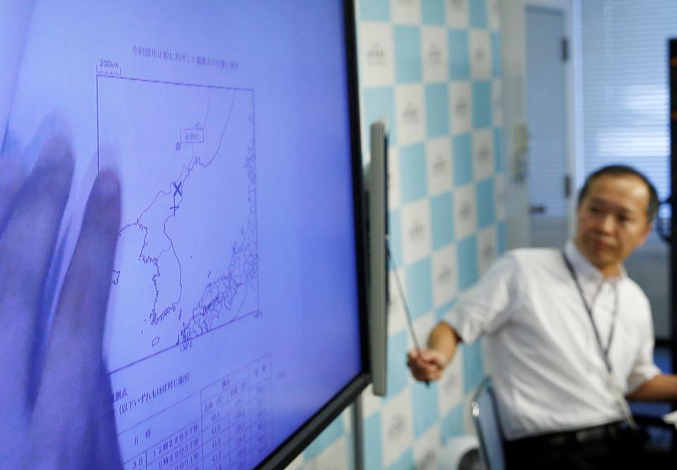 Japan Meteorological Agency's earthquake and tsunami observations division director Toshiyuki Matsumori speaks next to a monitor showing graphs of ground motion waveform data observed in Japan