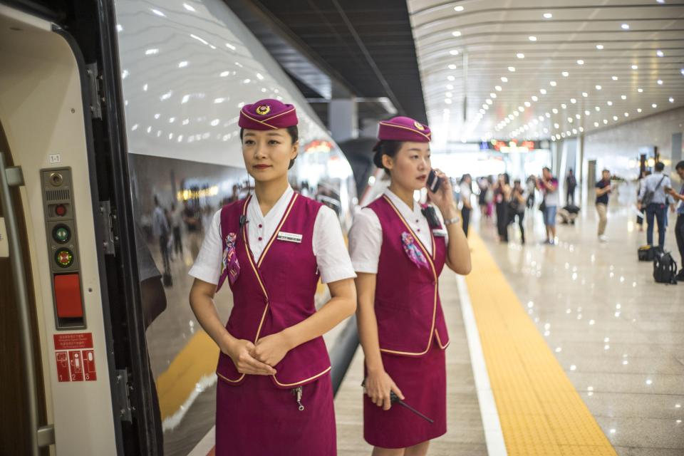 Chinese hostesses welcome passengers on the platform before they board the train