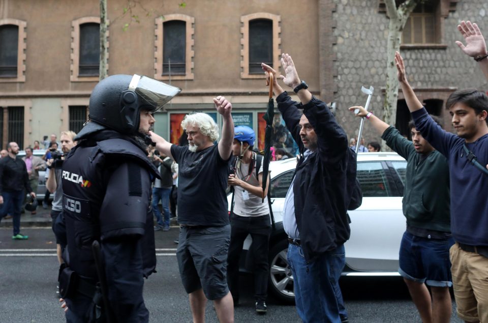 Protesters hold their hands above their heads in front of riot police 