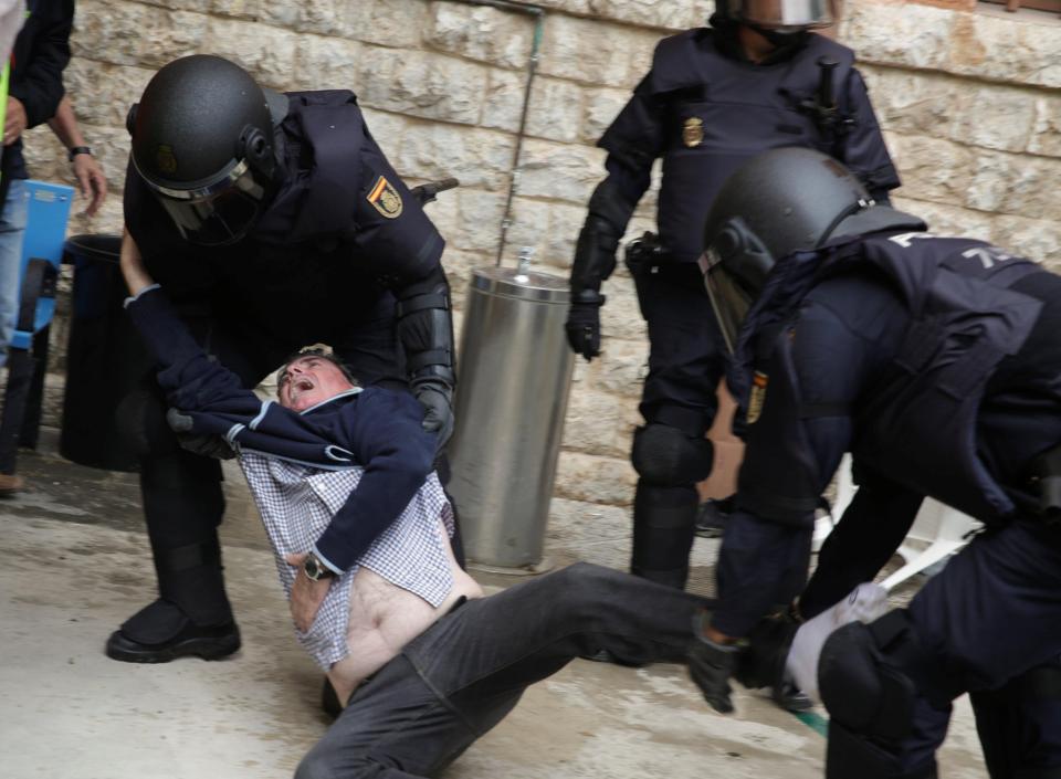 A man screams as he is dragged away from a polling station in Tarragona