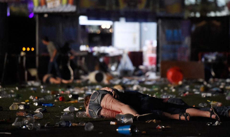 A woman lies on the ground, covered in blood