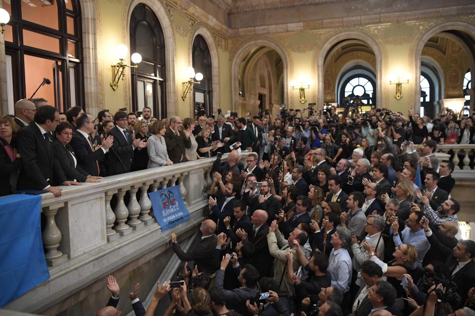 Separatist lawmakers hold their ceremonial staves into the air after a vote on independence in the Catalan parliament