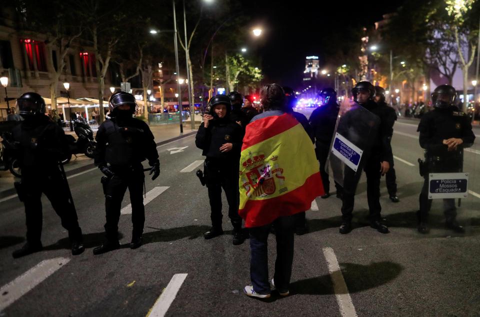 A pro unity demonstrator stands in front of Catalan Regional Police officers during a protest