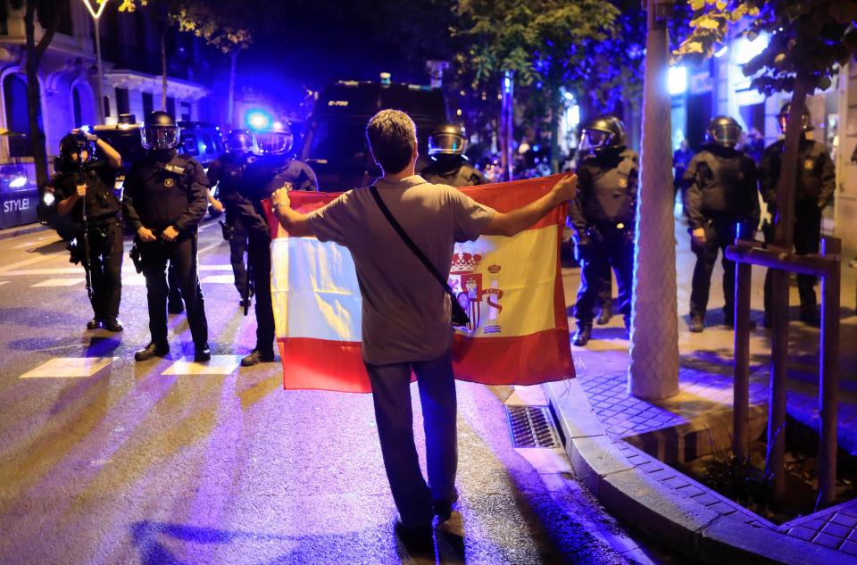  A pro unity demonstrator displays a Spanish flag to Catalan Regional Police officers during a protest