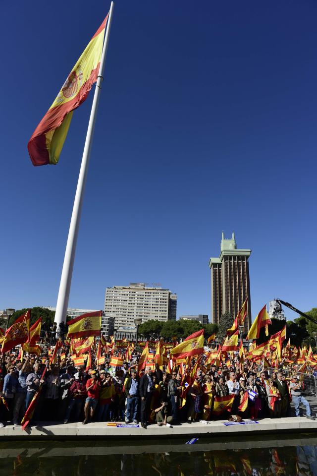People wave Spanish flags during a demonstration calling for unity at Plaza de Colon in Madrid